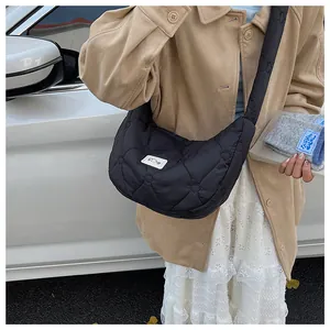 Detail of black heart-quilted dumpling bag with white label on casual crossbody strap