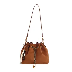 Minimalist caramel brown drawstring bucket bag with beads and thin leather shoulder strap