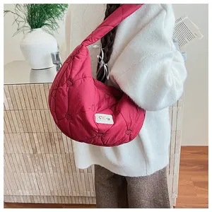 Detail of red heart-quilted puffer dumpling bag with a white logo and zipper closure