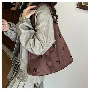 Close-up of brown suede tote bag featuring intricate laser-cut hollow floral patterns