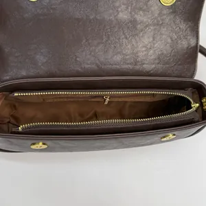 Brown leather underarm bag with gold metal zippers and internal compartments