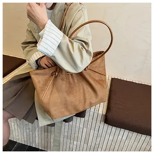 Detail of a brown suede tote bag featuring elegant knot accents and a soft matte texture