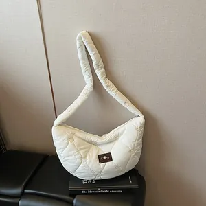 White heart quilted hobo bag with brown leather patch on black books in minimalist scene