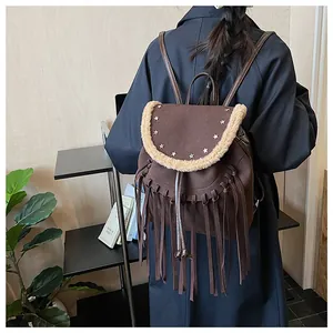 Détail du sac à dos en daim marron avec des franges et des rivets en forme d'étoile