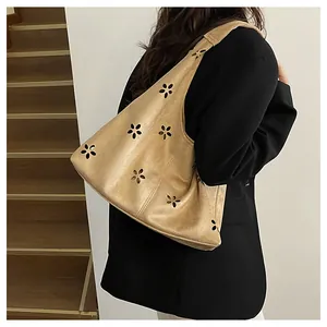 Detail of khaki cutout tote bag made of suede-like material shown on female model's shoulder