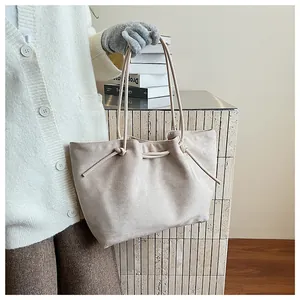 Detail of minimalist cream tote bag with tie-knot drawstring and textured suede finish