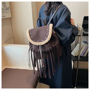 Détail du sac à dos en daim marron avec rivets en étoile, bordure en fourrure et franges