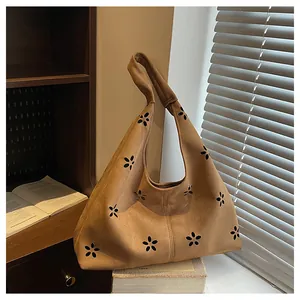 Macro detail of camel suede tote bag featuring hollow flower patterns and soft matte texture