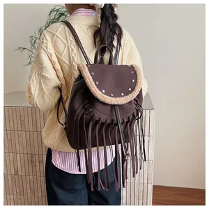 Vue détaillée d'un sac à dos marron à franges avec clous étoiles porté par un mannequin