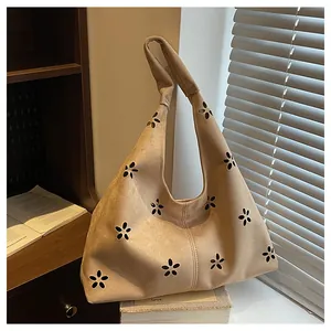 Detail of apricot hobo bag with floral laser-cut patterns and soft suede texture