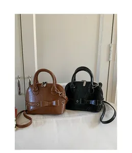 Close-up of mini shell bags in brown and black with bow detail and metallic eyelets