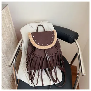 Détail d'un sac à dos marron à franges avec clous étoiles et bordure en fourrure sur cuir