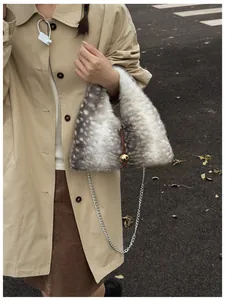 Detail of faux fur triangle bag with deer print pattern and gold ball ornament