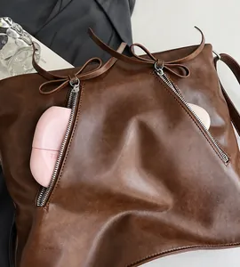 Detailansicht der braunen Vintage-Ledertasche mit silbernen Reißverschlüssen und Schleifen
