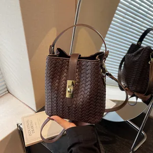 Retro dark brown woven bucket bag with gold metal lock and adjustable shoulder strap