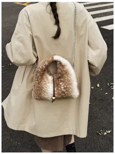 Detail of plush faux fur triangle bag with gold ball charm and chain strap