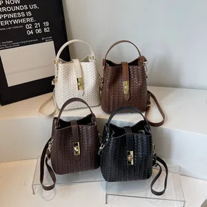 Modern woven bucket bag in four neutral colors with metallic clasp and adjustable strap