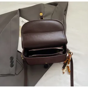 Overhead detail of brown matte crossbody bag with dual compartments and bead charm