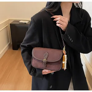 Detail of vintage brown suede crossbody bag featuring elegant beaded charm and metal buckle
