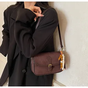 Close-up of retro brown matte leather shoulder bag with decorative beaded tassel detail