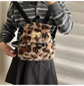 Detail of faux fur leopard print backpack featuring a decorative golden bow and straps