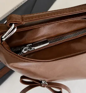 Detail der dunkelbraunen Leder-Tote mit glattem Silber-Reißverschluss und Schleife