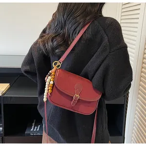 Detailed shot of dark burgundy matte leather crossbody bag with ethnic beaded tassel