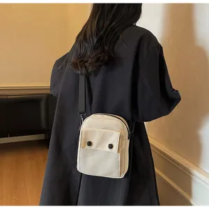 Rear view of a model wearing the cream canvas crossbody bag with black adjustable strap
