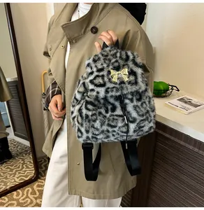 Detailed close-up of plush leopard print backpack featuring a gold bow metallic clasp