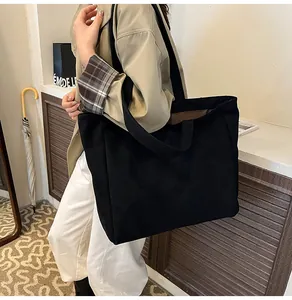 Close-up of the wide black shoulder strap and durable canvas material of the tote bag