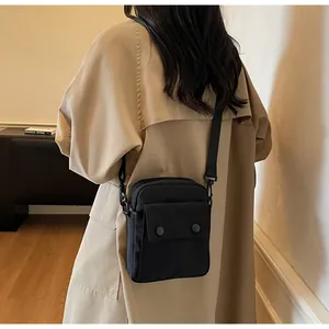 Detail of minimalist black canvas crossbody bag with front pocket and adjustable strap