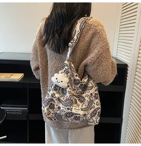 Detail of floral paisley canvas tote bag with a white plush cloud charm on shoulder strap