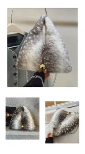 Close-up of spotted plush triangle bag with golden ball lock and metal chain strap