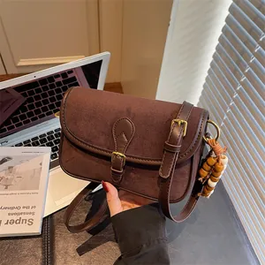 Retro brown frosted suede messenger bag with wooden bead charm in a lifestyle setting