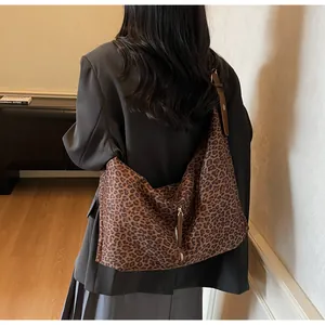 Detailed view of leopard print tote bag with metal zipper and brown leather strap
