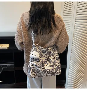 Detail of paisley canvas shoulder bag with plush cloud charm and woven label