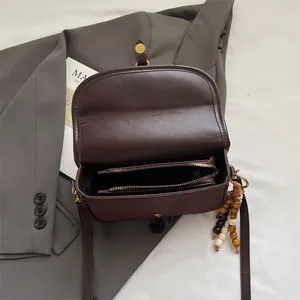 Dark brown matte saddle bag for women with tassel charm and dual zipper compartments