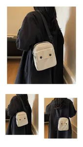 Detail of minimalist canvas crossbody bag with twin black buttons and adjustable strap