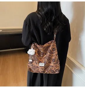 Detail of brown paisley canvas shoulder bag featuring a cute white cloud plush charm accessory