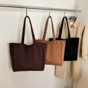 Large minimalist suede tote bag in brown and black shown hanging on a stand