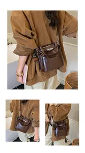 Detail of dark brown leather bucket bag with silver twist lock and woven handle