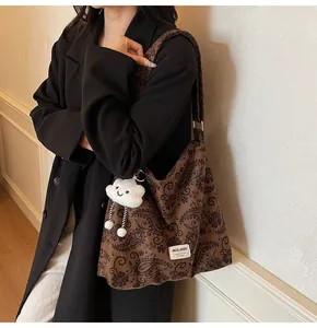 Detail of leopard paisley print shoulder bag with cute white cloud plush keychain accessory