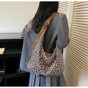 Detail of leopard print hobo bag featuring wide brown leather strap and gold metal buckle