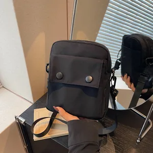 Minimalist black canvas crossbody bag with adjustable strap and front snap pockets