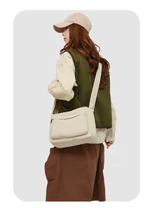 Modèle portant une sacoche en nylon crème avec fermeture éclair pour un style décontracté