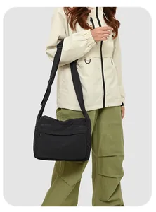 Détail du sac à bandoulière en nylon noir avec sangle réglable et poche zippée dissimulée