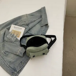 Minimalist light green canvas crossbody bag with adjustable black strap and dual snap buttons