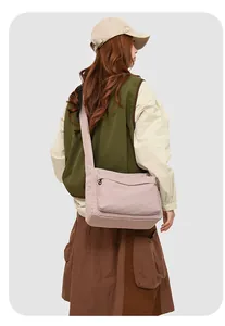 Sac bandoulière en nylon rose imperméable porté avec veste verte et jupe longue