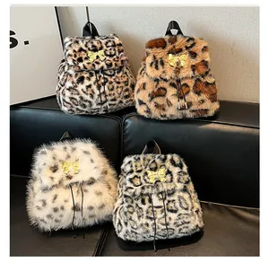 Detail showing four plush animal print backpacks with gold bows on a black leather sofa