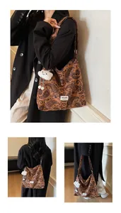Detail of a brown paisley canvas tote bag featuring a plush cloud charm and label